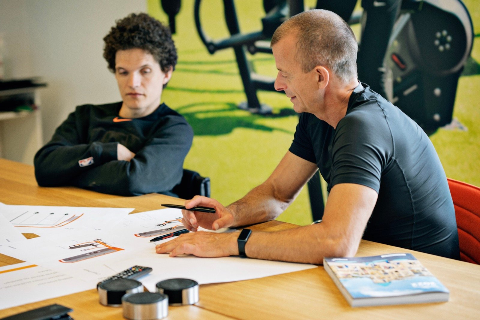Morten Zacho gennemgår produkttegninger med en kollega ved et mødebord.